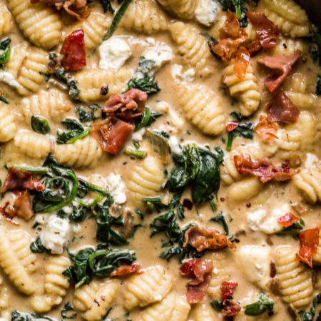 Overhead close up of blue cheese gnocchi tossed with prosciutto and spinach.