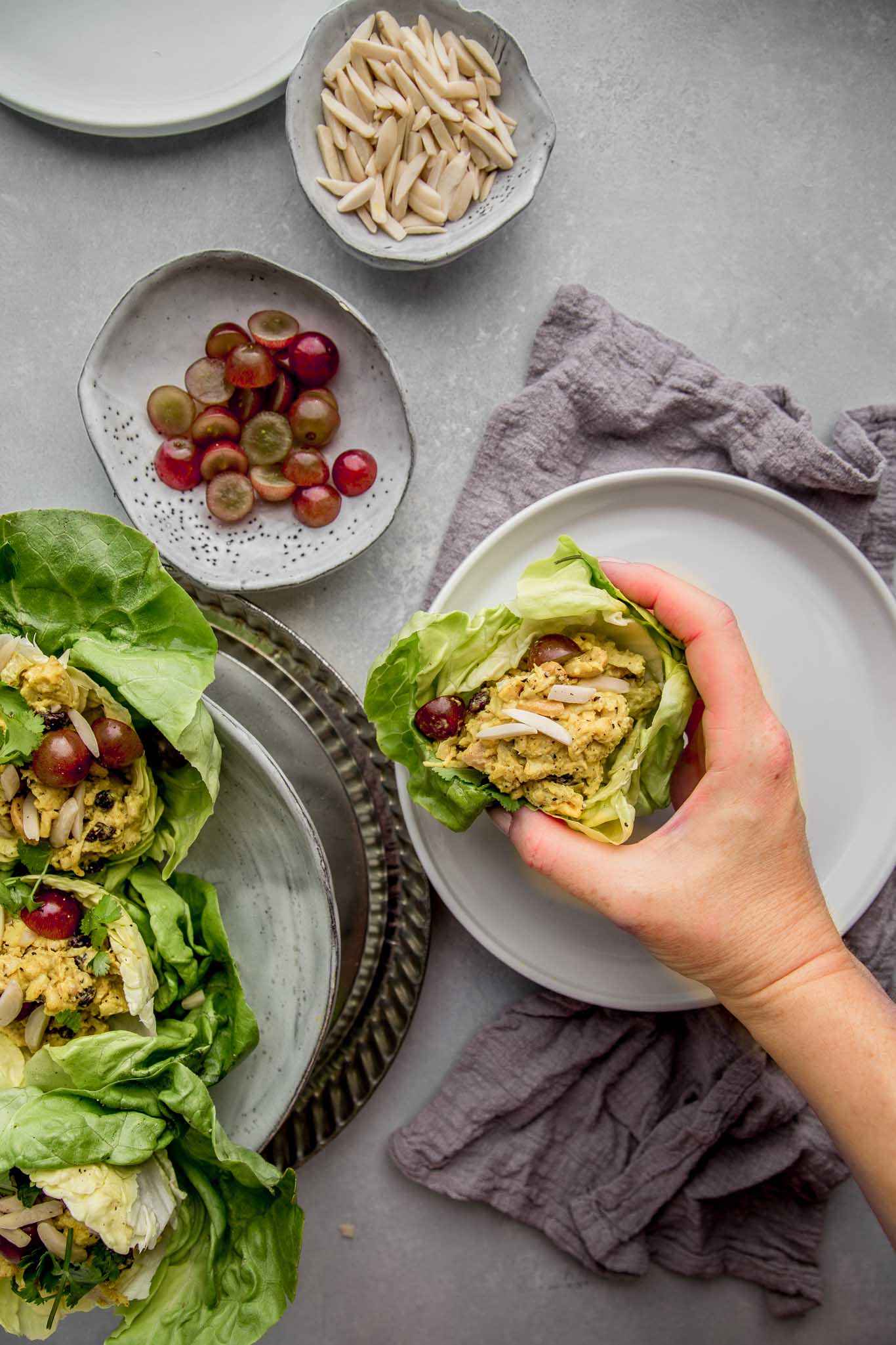 Hand reaching for curry chicken salad lettuce wrap.