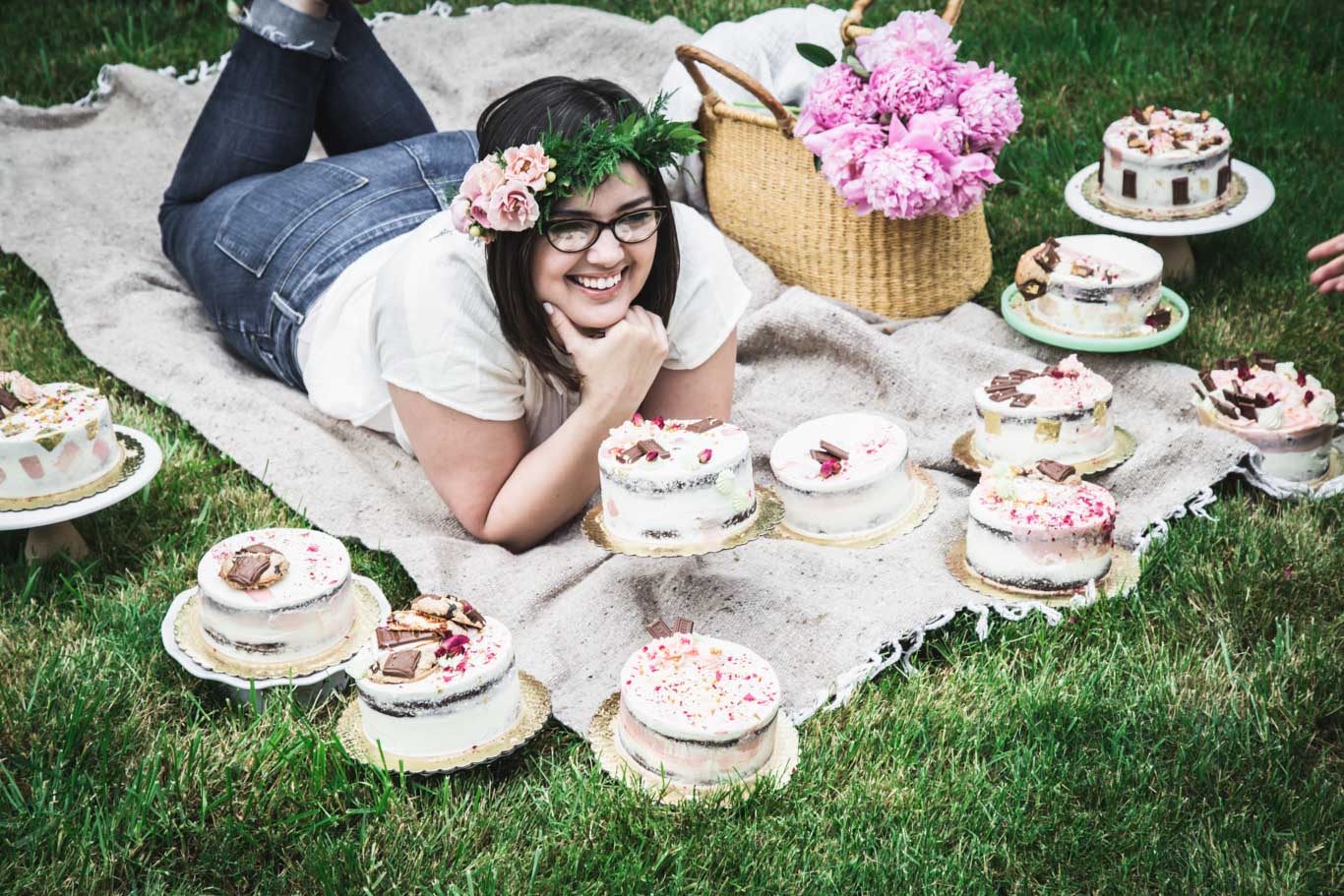 Karlee in grass surrounded by lots of decorated cakes.