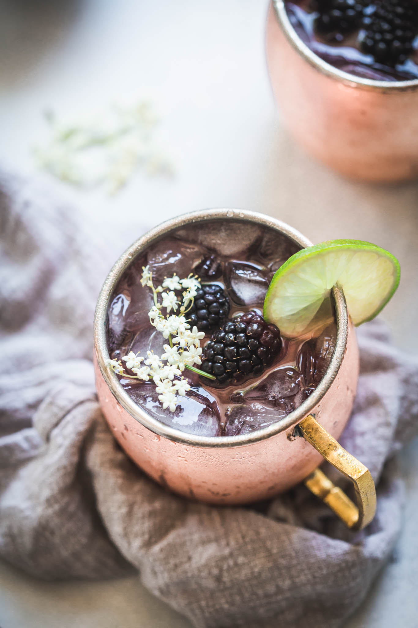 Close up of blackberry moscow mule topped with elderflowers