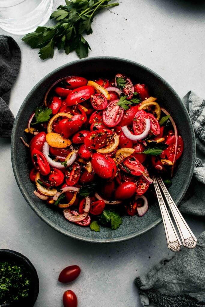 Overhead shot of cherry tomato salad in grey bowl.