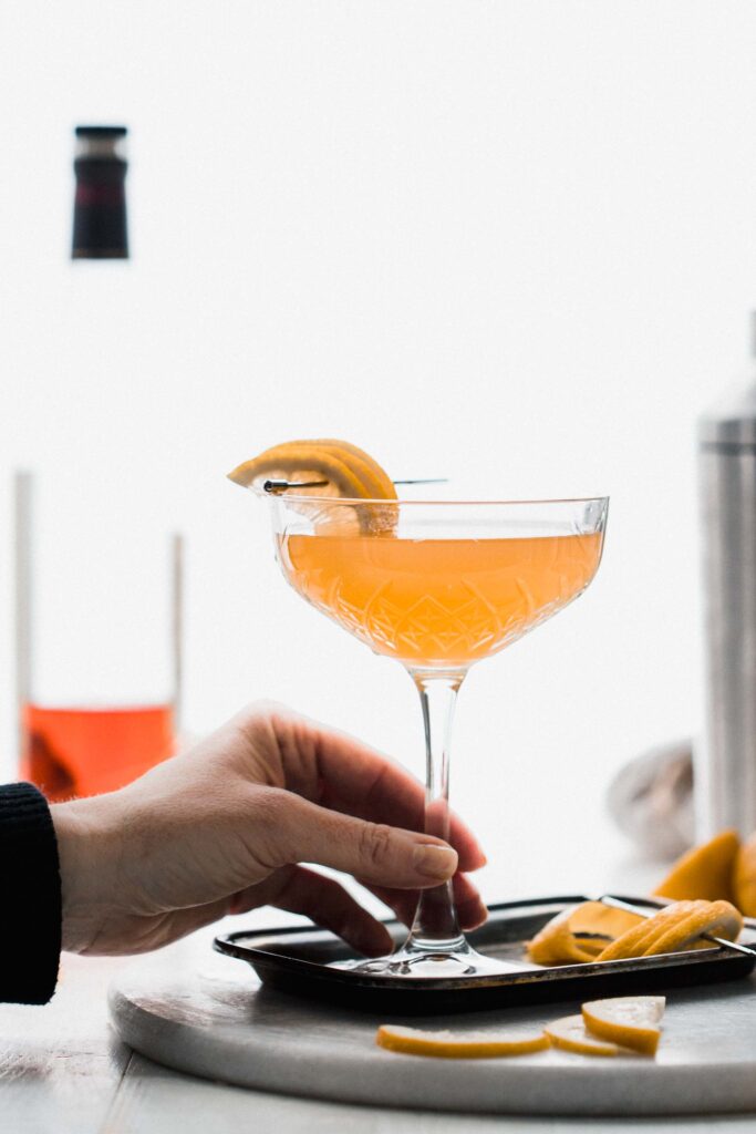 Hand holding glass of applejack cocktail. 