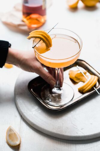 HAND HOLDING COUPE OF HARVEST MOON COCKTAIL