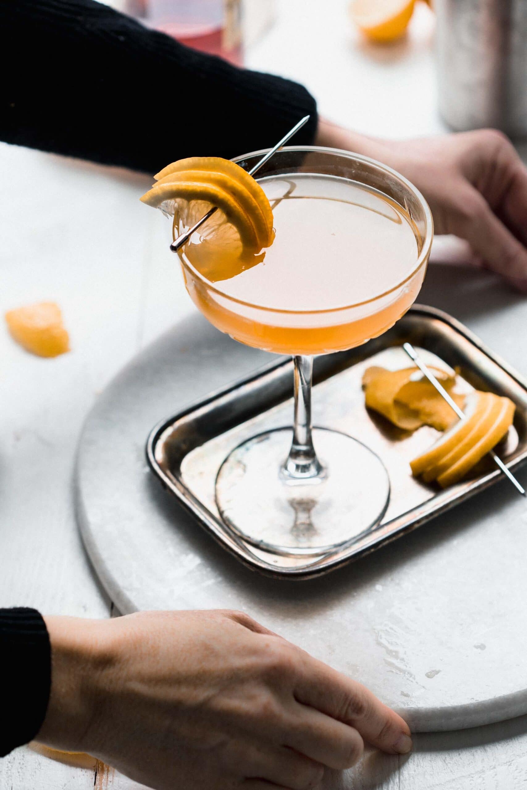 HANDS HOLDING TRAY WITH APPLEJACK COCKTAIL