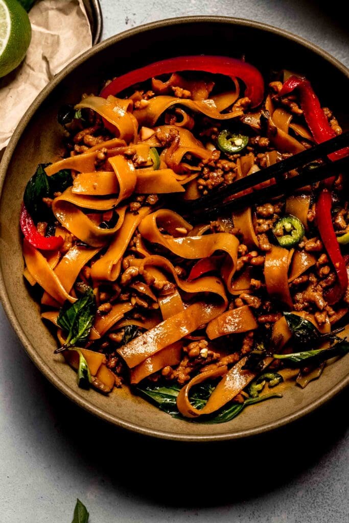 Prepared pad kee mao in brown bowl with chopsticks. 