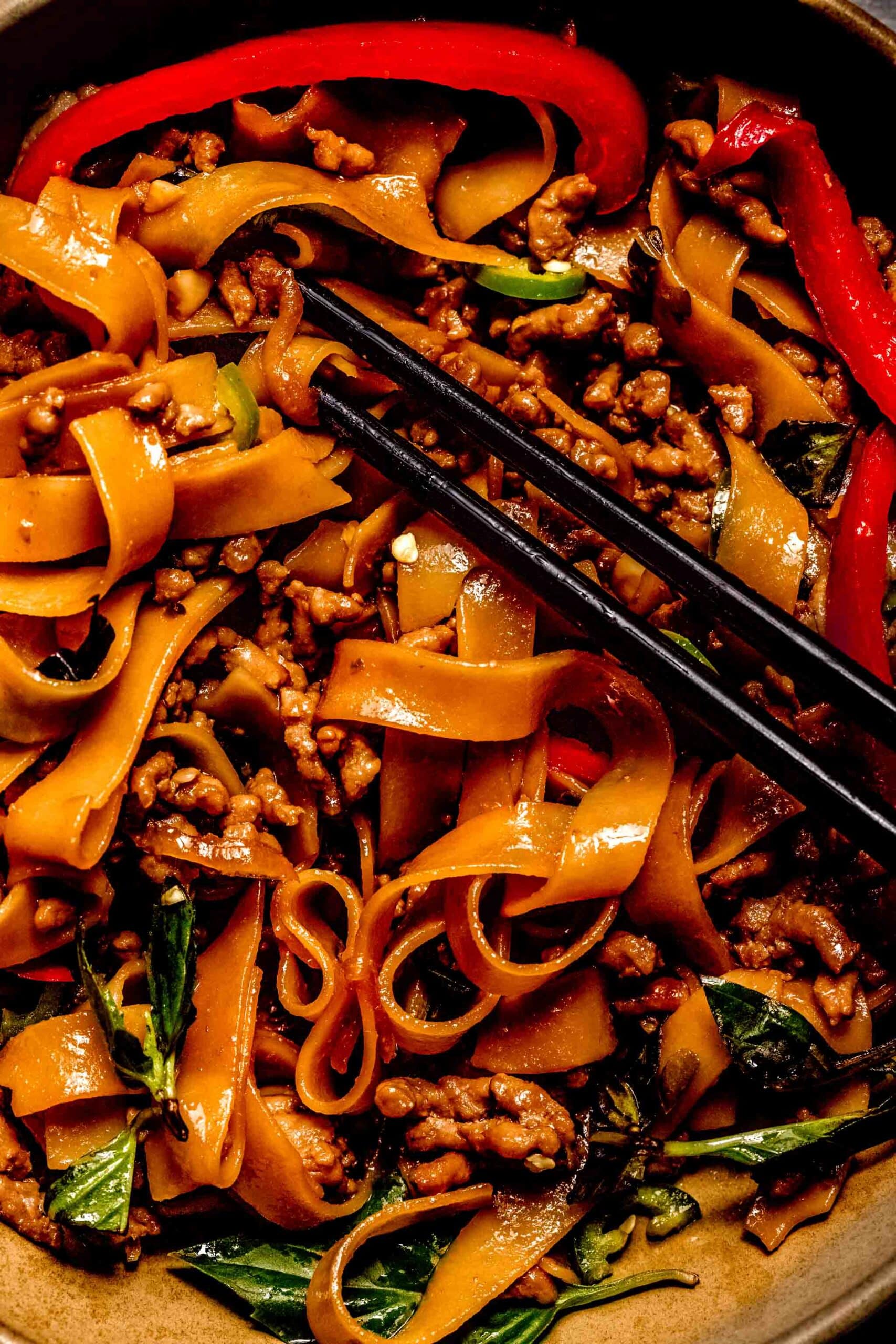 Overhead close up of bowl of pad kee mao noodles with chopsticks.