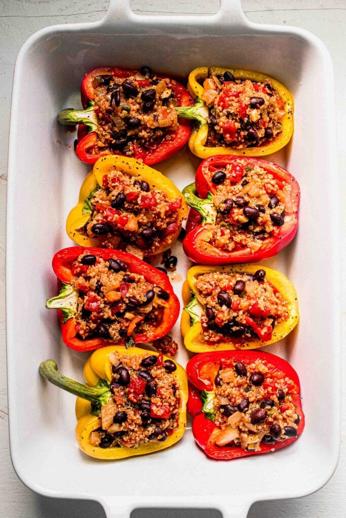 Stuffed peppers in baking dish before cooking and topping with cheese. 