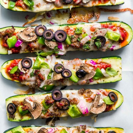 Overhead shot of zucchini pizza boats with supreme toppings.