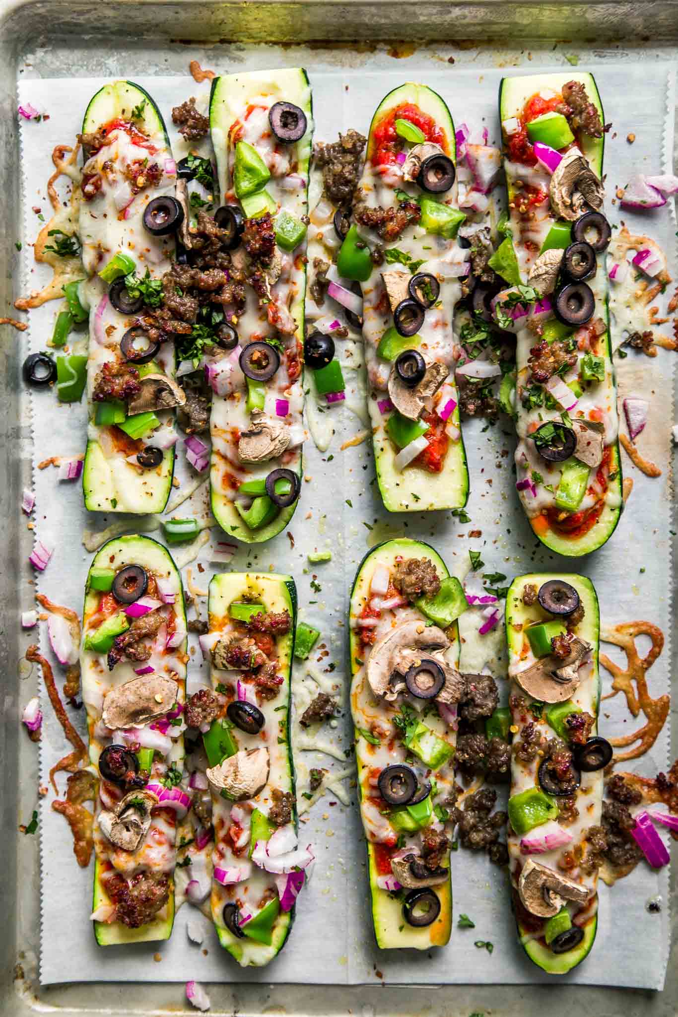 Overhead shot of zucchini pizza boats on baking sheet.