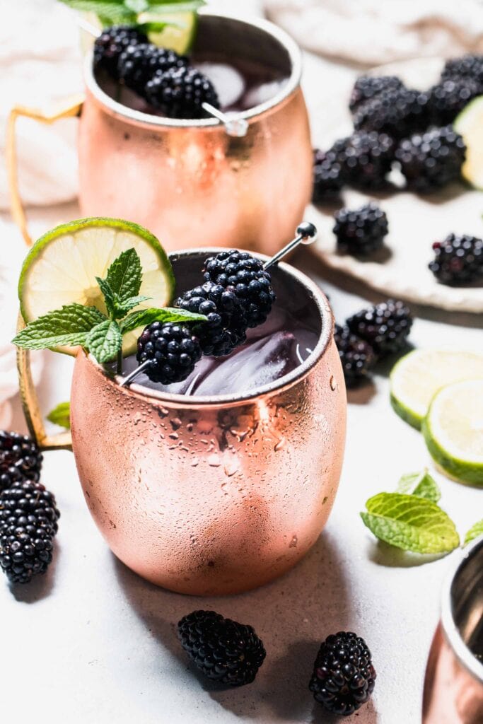 Mule in copper mug garnished with fresh mint, lime wheel and blackberries.