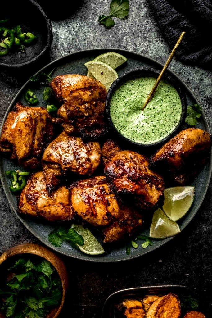 Overhead shot of grilled chicken on plate with green sauce. 