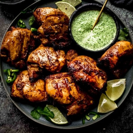 Plate of peruvian chicken on plate with green sauce.