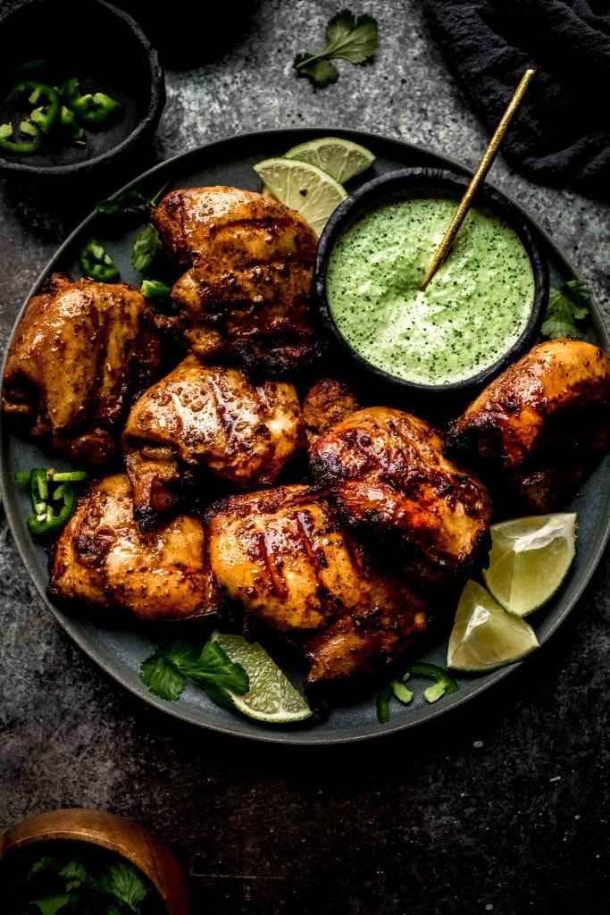 Plate of peruvian chicken on plate with green sauce.