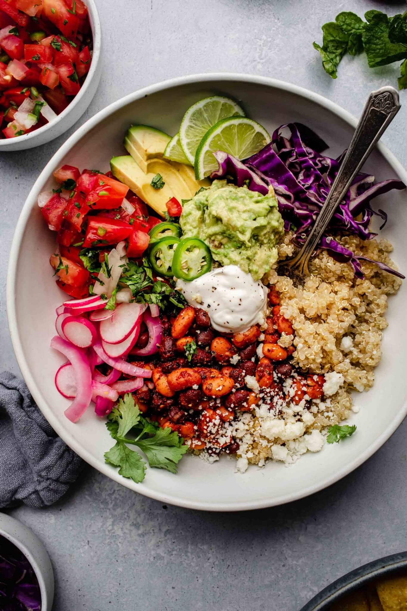 Quinoa burrito bowl arranged next to bowl of salsa with spoon.