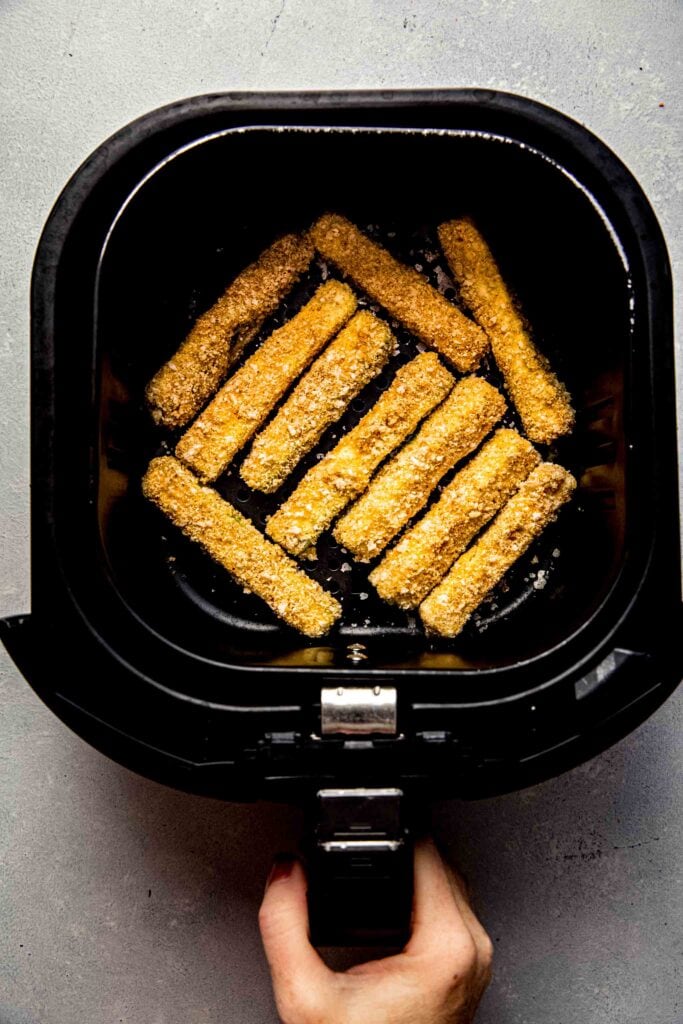 Uncooked zucchini fries in air fryer. 