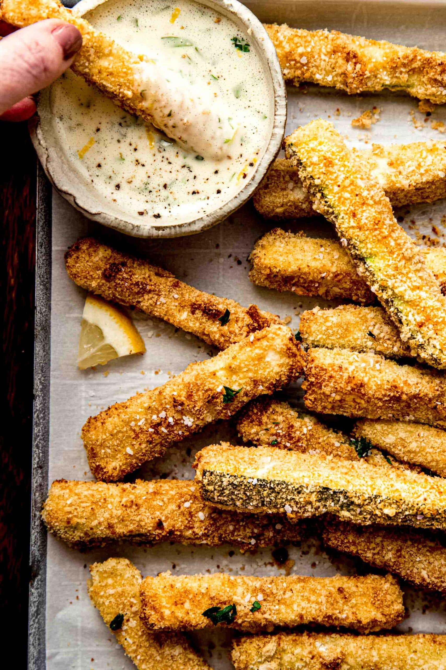 Hand dipping zucchini fry into aioli.