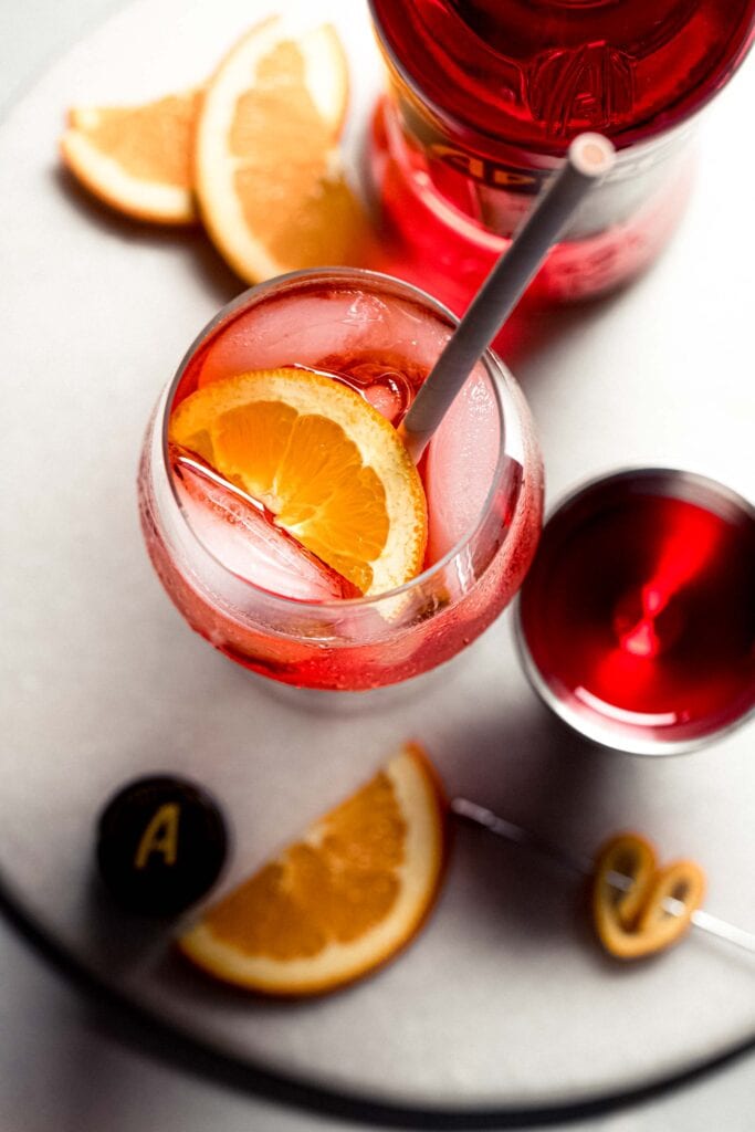 Overhead shot of spritz in glass next to jigger of aperol.