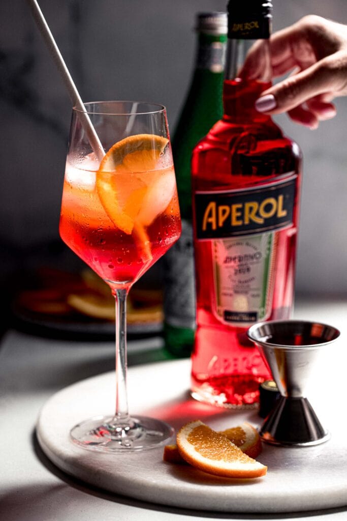 Hand reaching for bottle of aperol. 