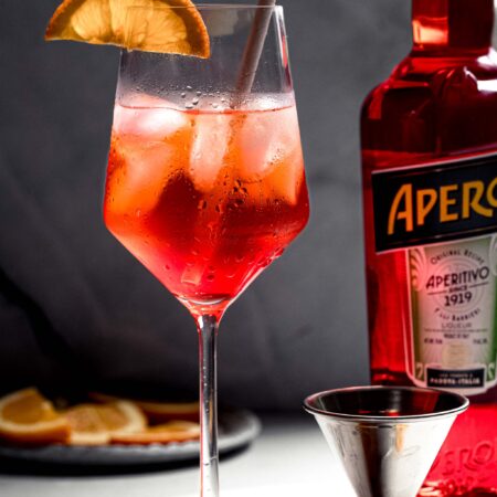 Aperol spritz in wine glass garnished with orange slice.