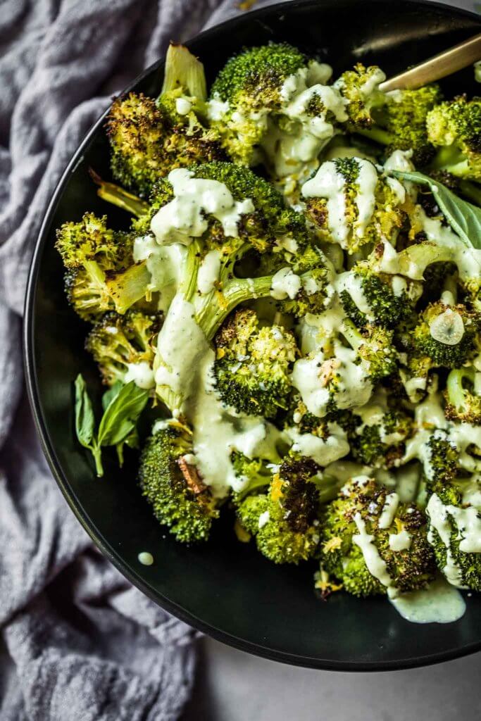 Overhead close up of roasted broccoli drizzled with basil tahini sauce.
