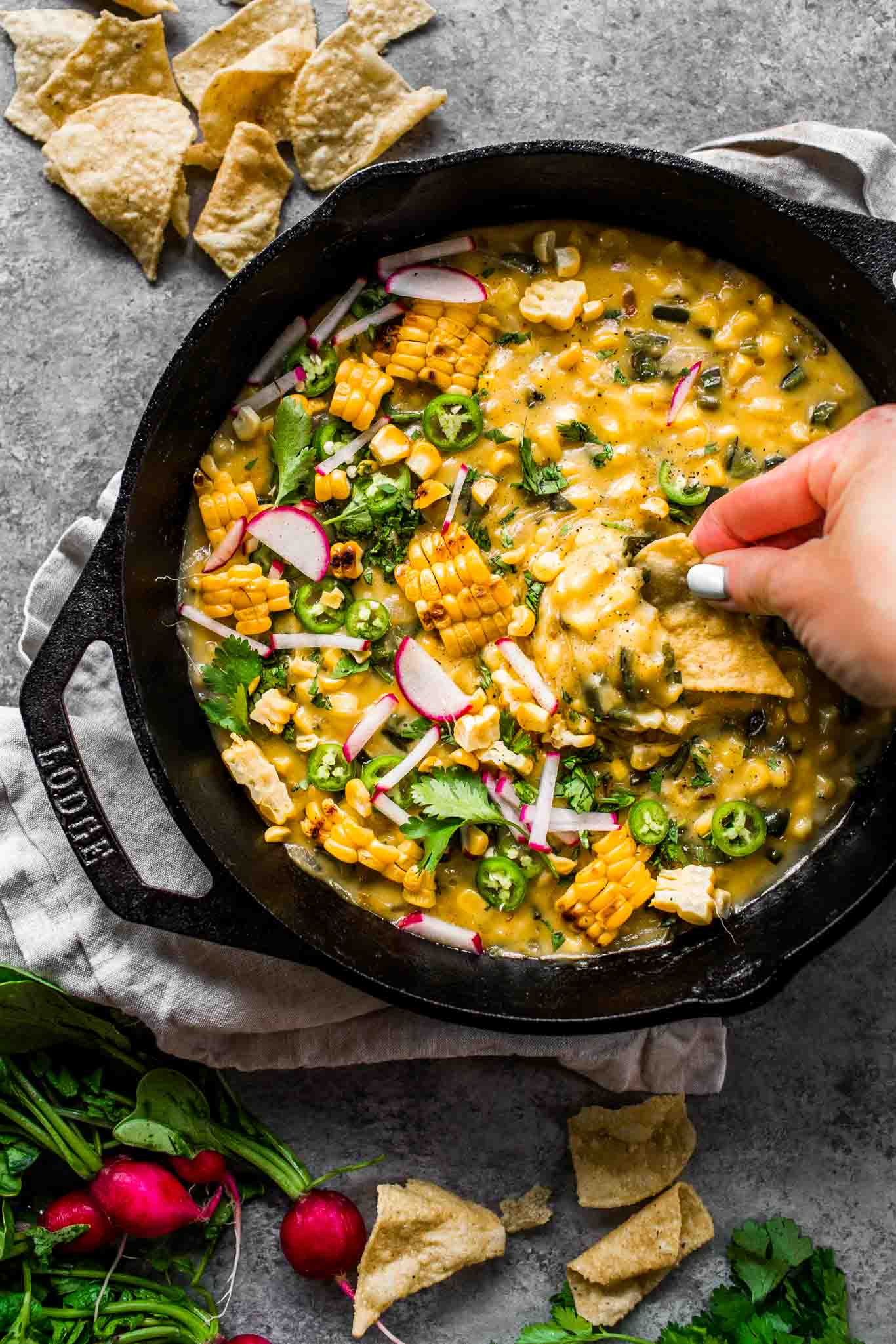 Hand dipping chip into corn queso dip