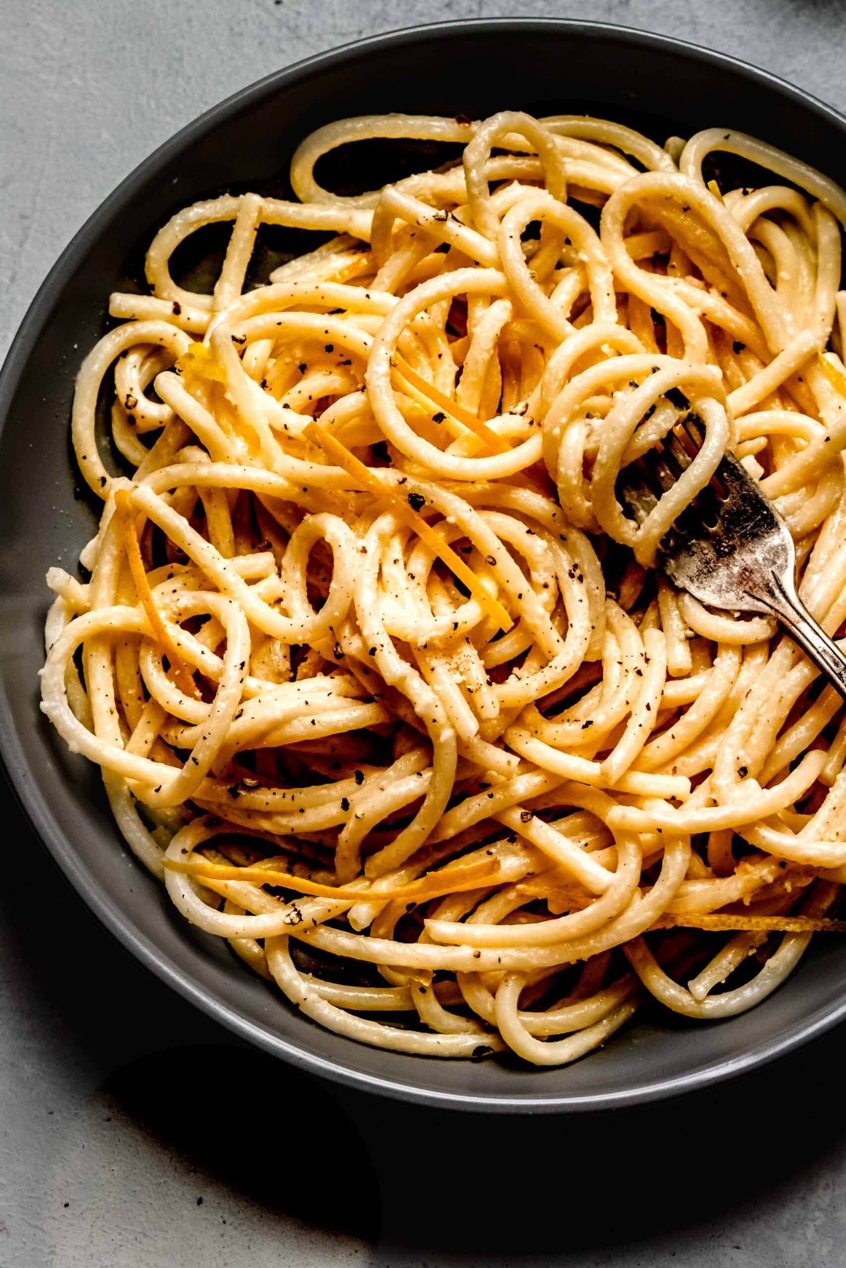 Lemon pasta in grey bowl with fork.