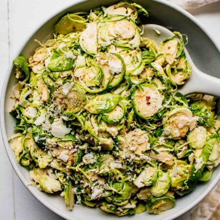 Shaved brussels sprouts salad in large bowl with serving spoon.