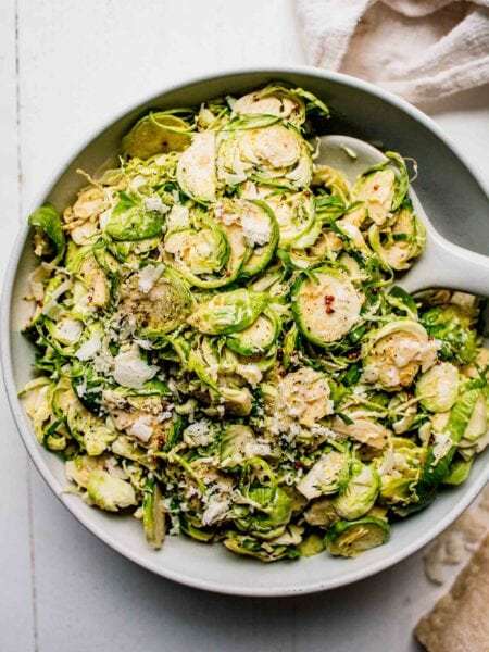 Shaved brussels sprouts salad in large bowl with serving spoon.