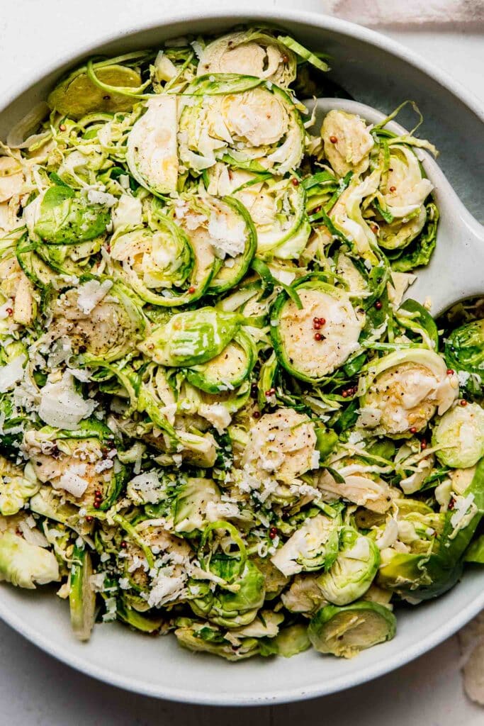 Close up of shaved brussels sprouts salad in white bowl. 