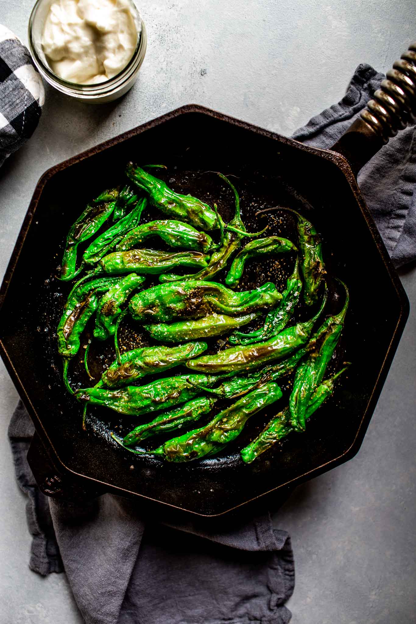 Blistered Shishito peppers in cast iron skillet. 