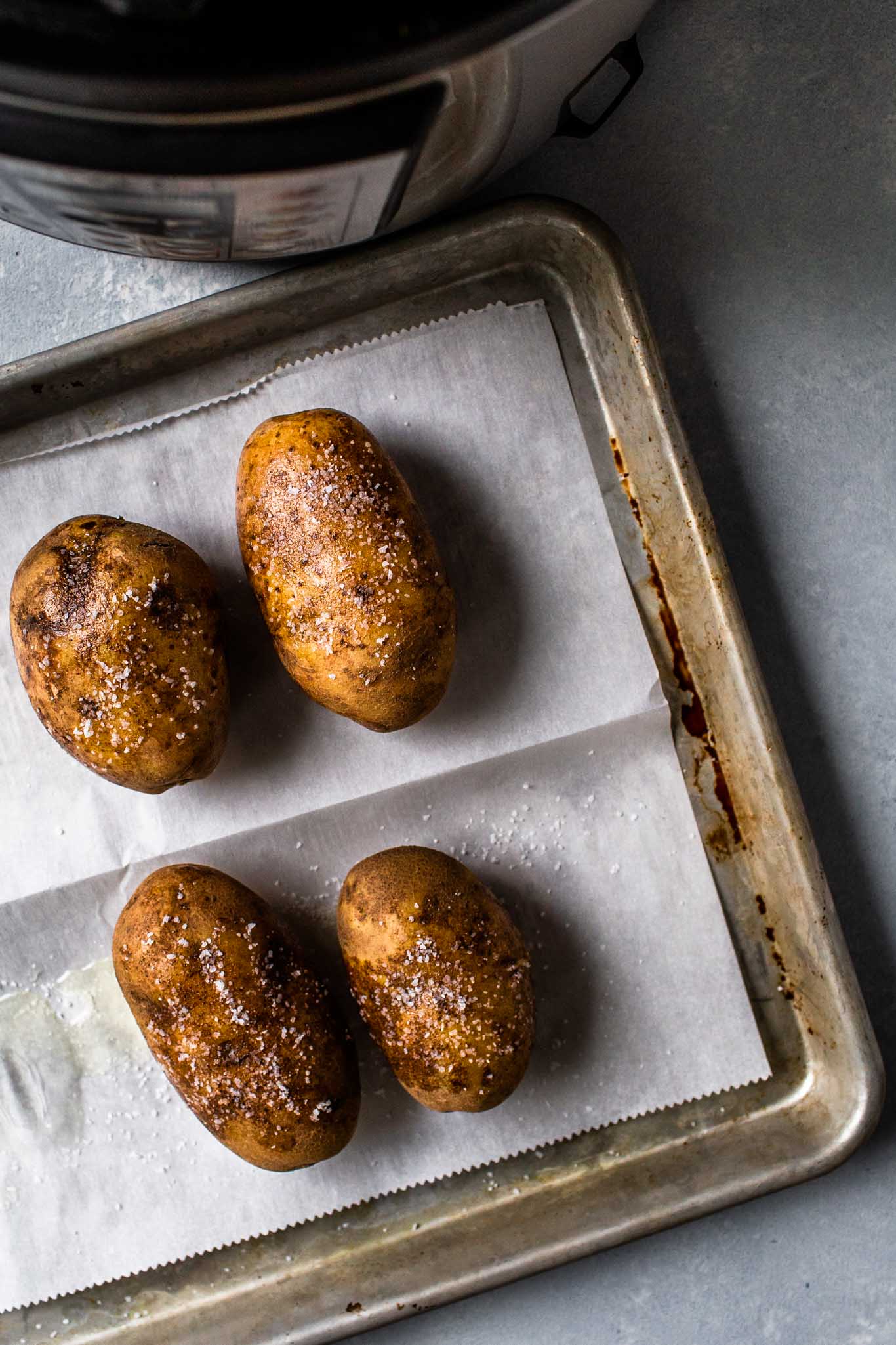 Potatoes on baking sheet next to instant pot.