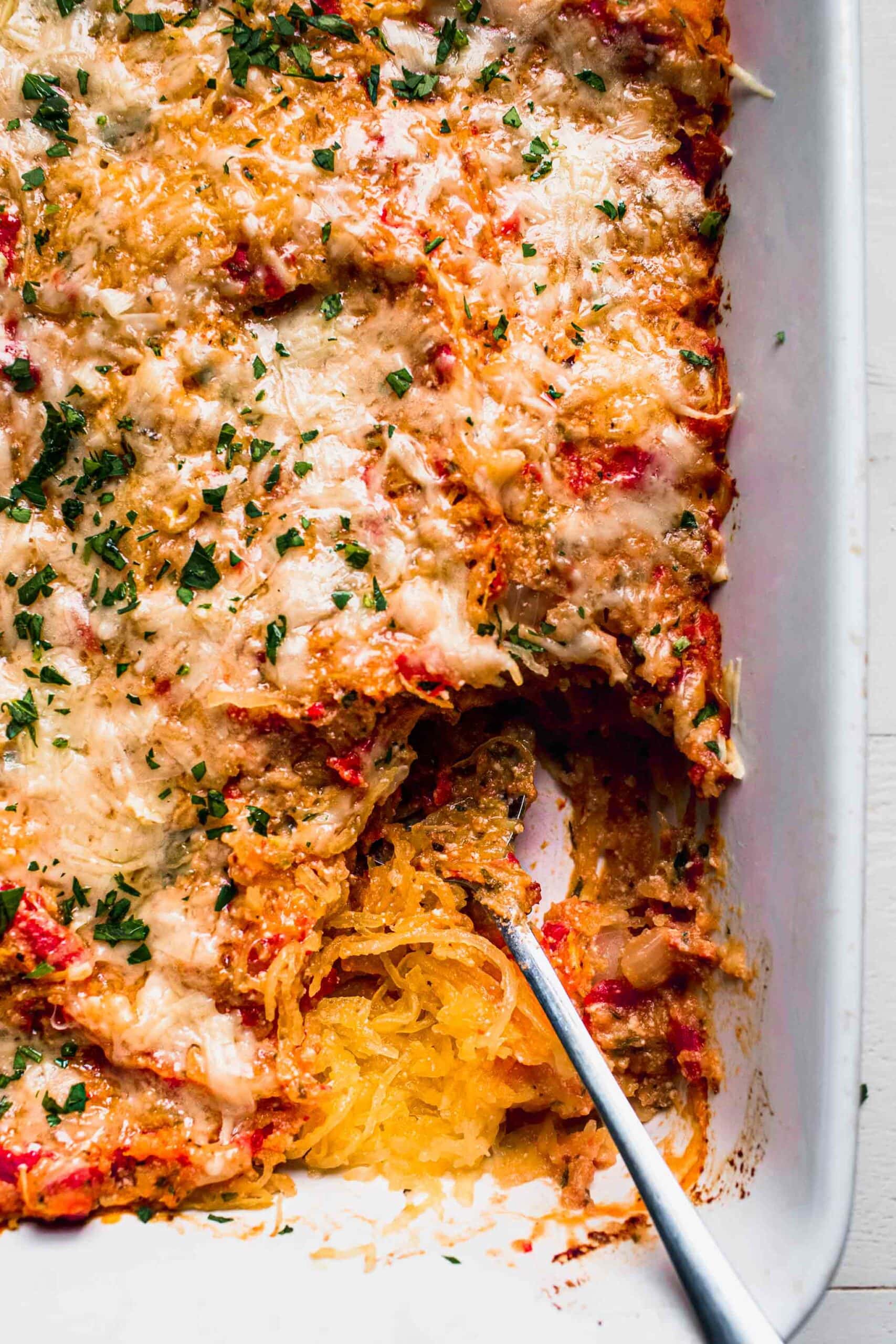 Spaghetti squash caserole in baking dish with serving spoon.