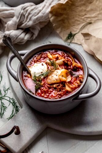 Bowl of cabbage roll soup topped with dollop of sour cream & fresh dill.