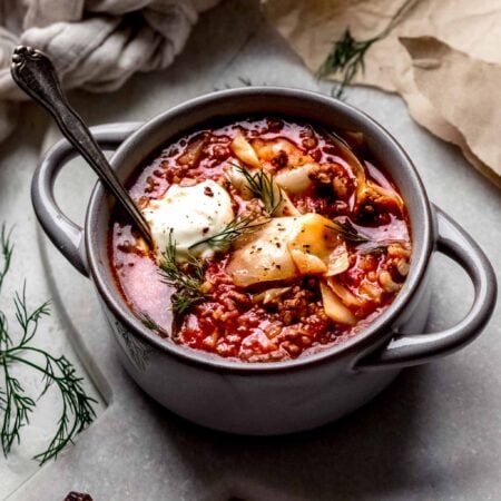 Bowl of cabbage roll soup topped with dollop of sour cream & fresh dill.