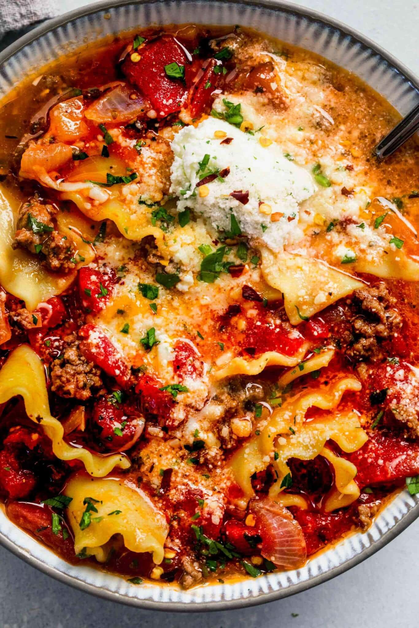 Overhead shot of bowl of lasagna soup topped with dollop of ricotta cheese.