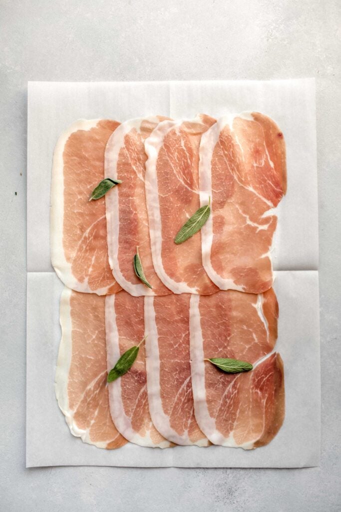 Pieces of prosciutto on parchment.