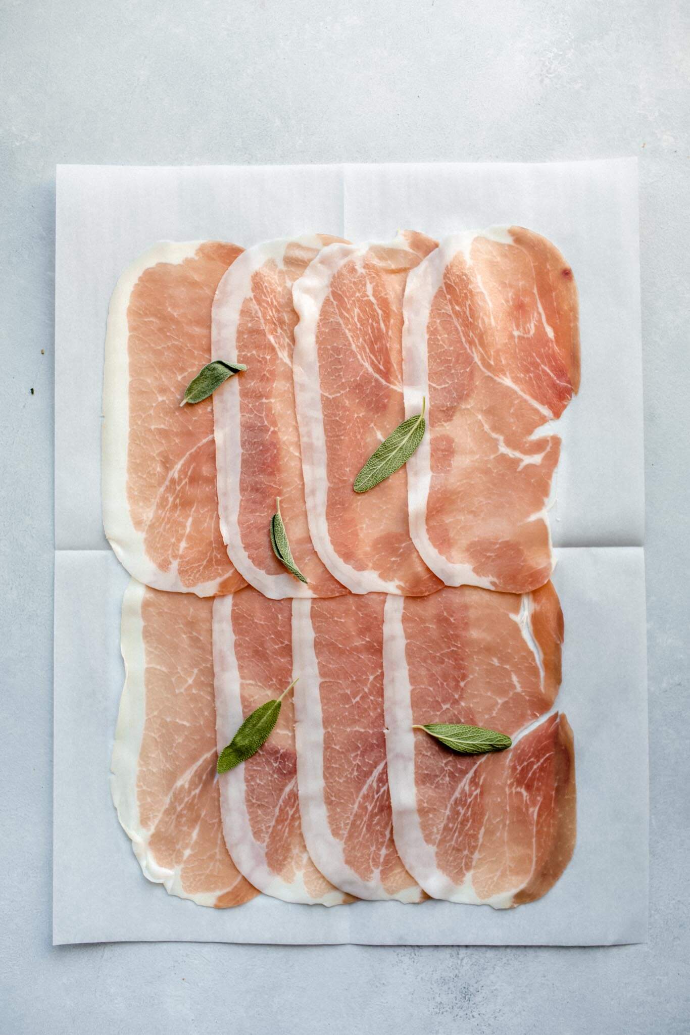 Prosciutto laid out in slices on parchment.
