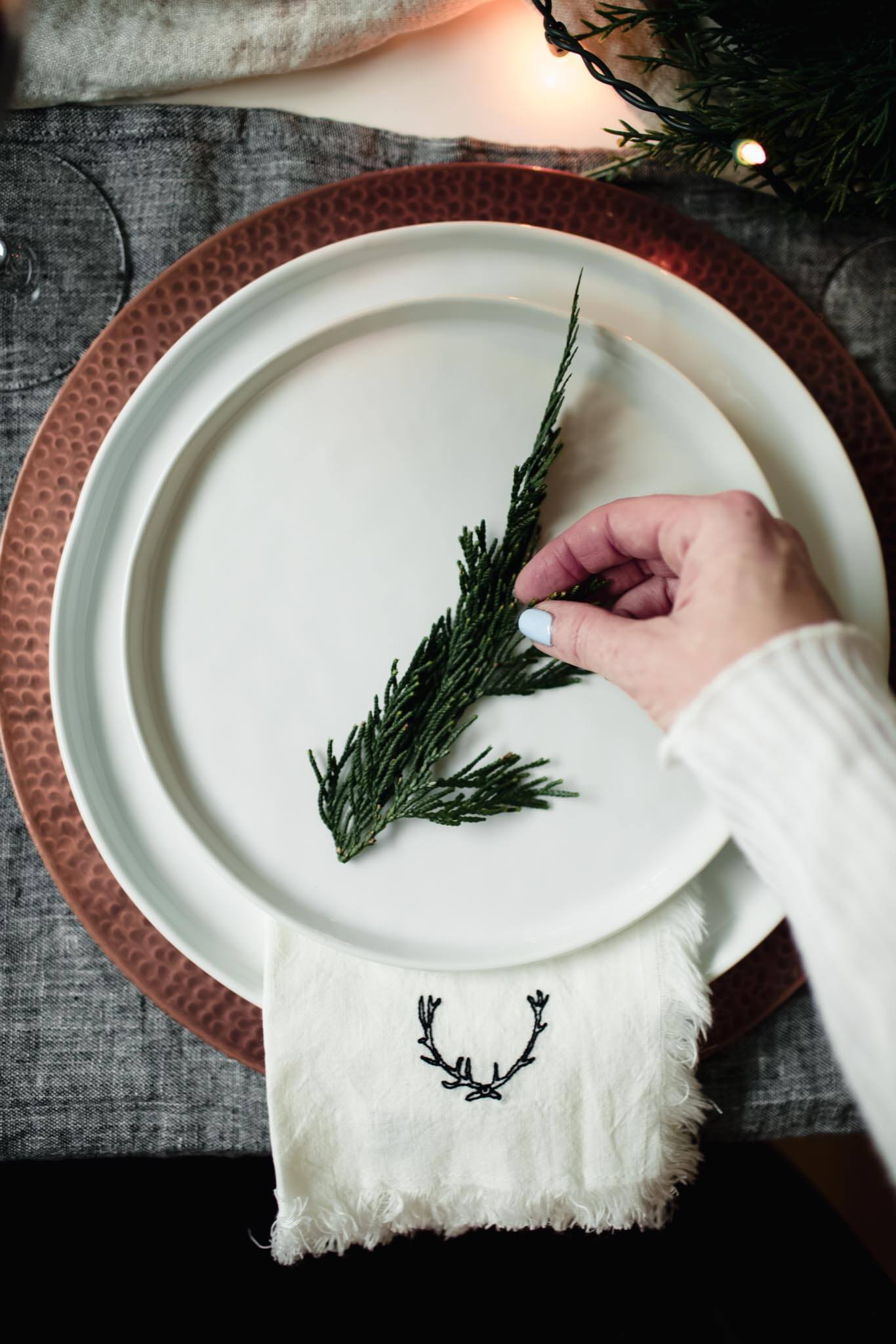 Table setting with white plates and pine sprig as decoration for the holidays.