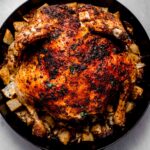 Roasted spatchcock chicken in skillet with potatoes and cabbage.