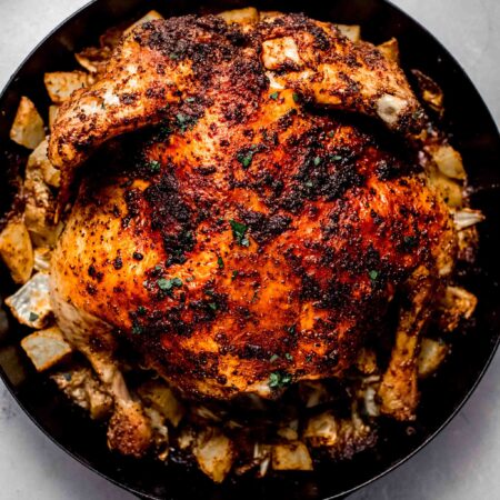 Roasted spatchcock chicken in skillet with potatoes and cabbage.