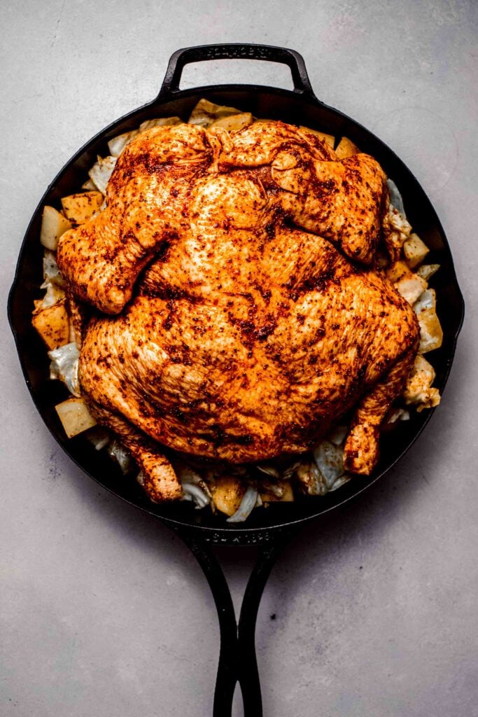Uncooked spatchcocked chicken arranged in skillet.