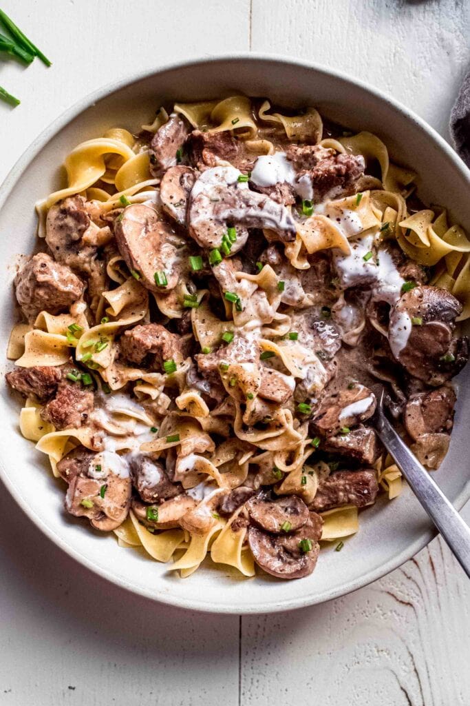 Overhead shot of stroganoff in serving bowl topped with chives. 