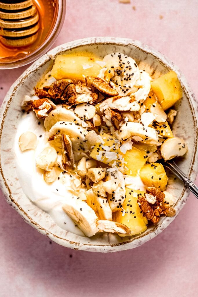 Greek yogurt bowl topped with pineapple, banana, chia seeds and honey.