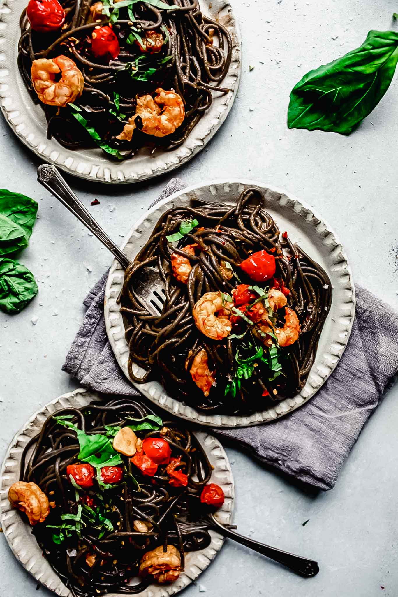 Three plates of squid ink pasta.