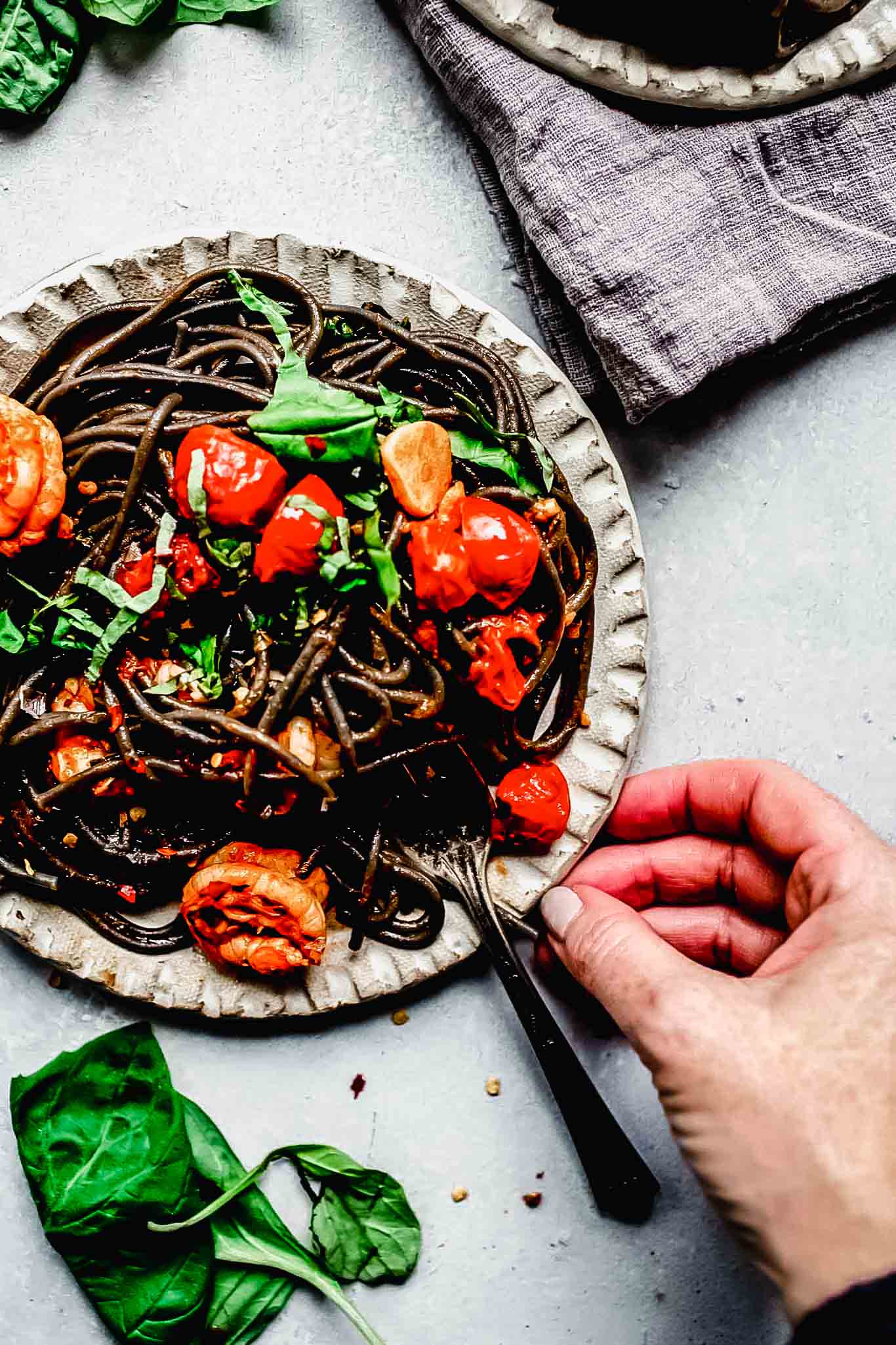 Hand reaching for plate of pasta.