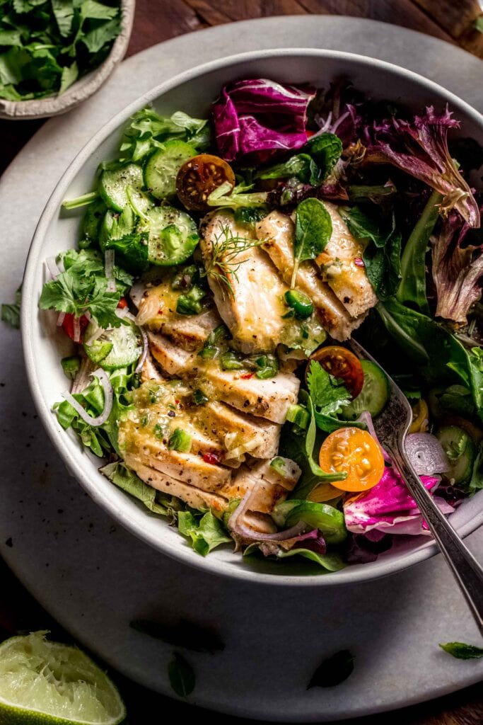 Lemongrass chicken salad in bowl with colorful toppings. 