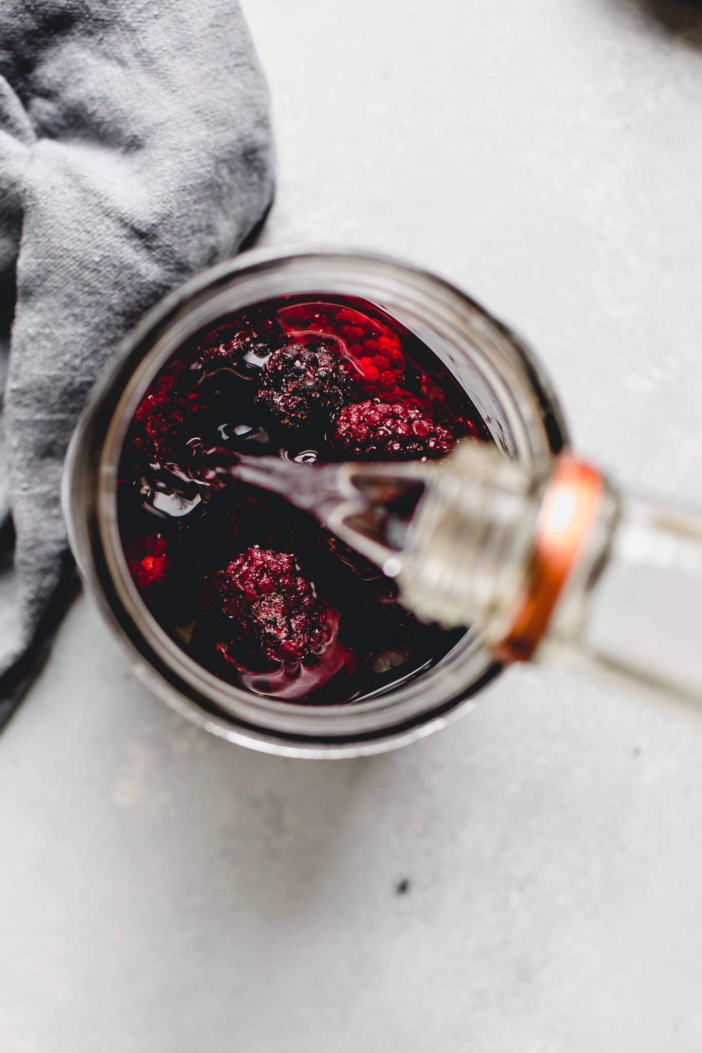 Pouring vodka into jar of berries.