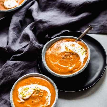 Side view of three bowls of carrot ginger soup.