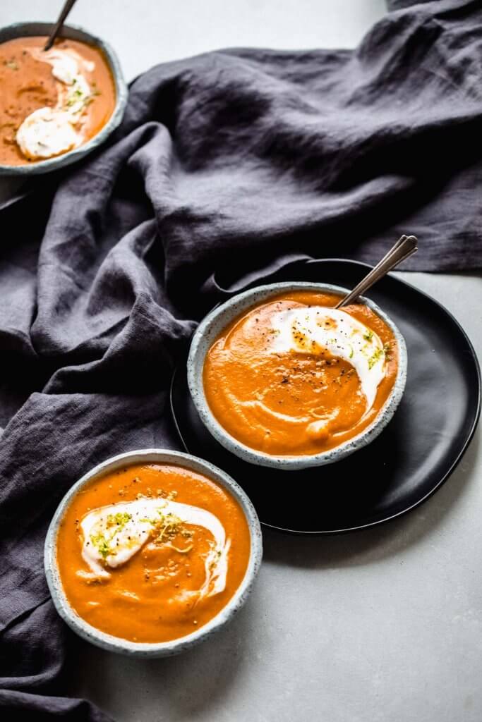 Side view of three bowls of carrot ginger soup.