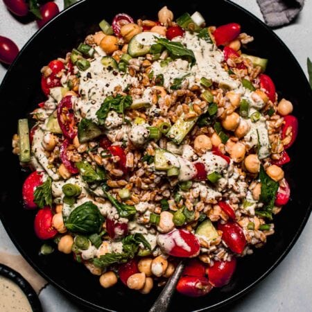 Overhead shot of farro salad in large black bowl with spoon.